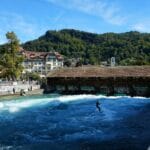 Surfer na rzecznej fali obok drewnianego mostu w Thun w Szwajcarii