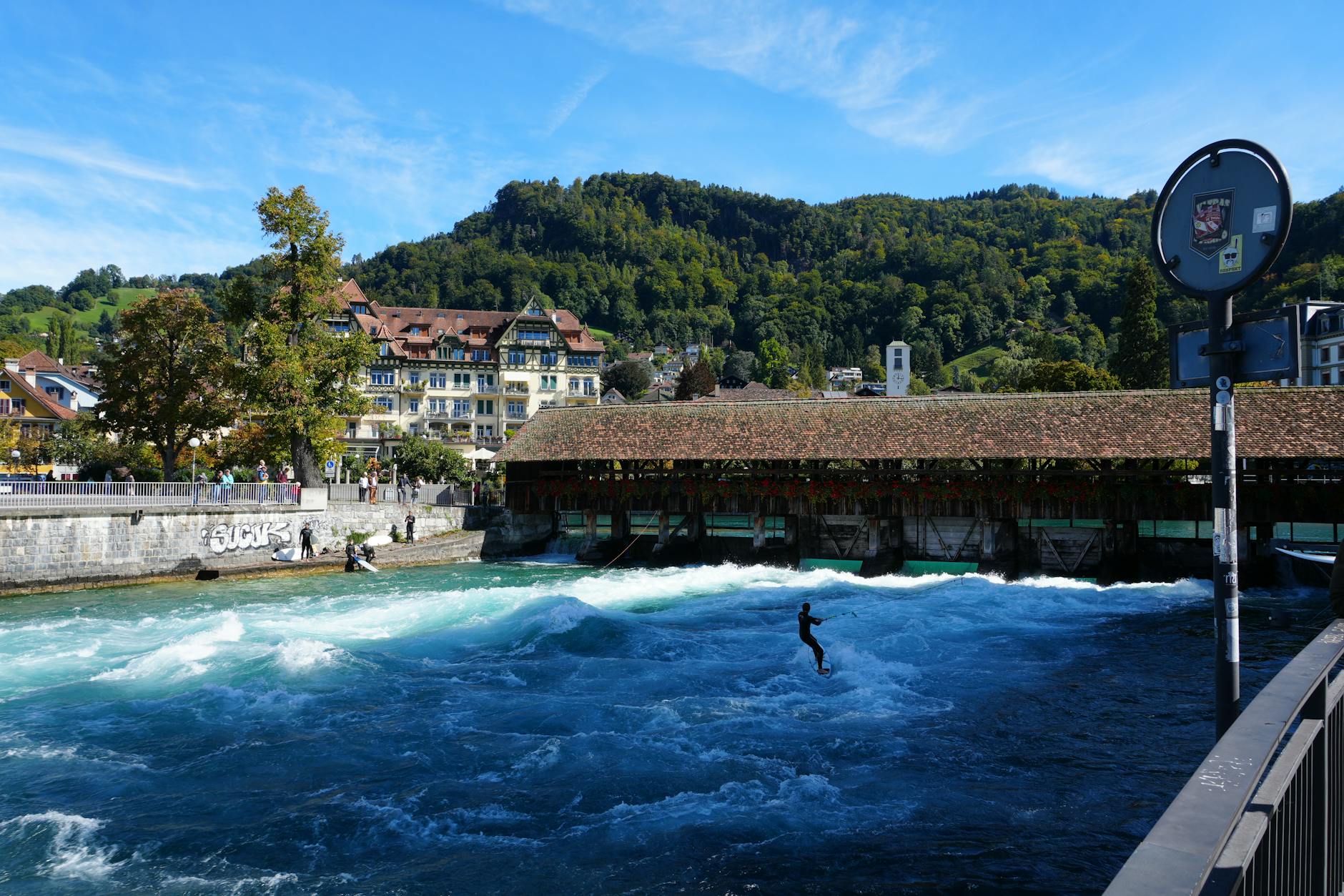 Surfer na rzecznej fali obok drewnianego mostu w Thun w Szwajcarii