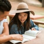 Uśmiechnięta azjatycka para czyta książki razem na świeżym powietrzu