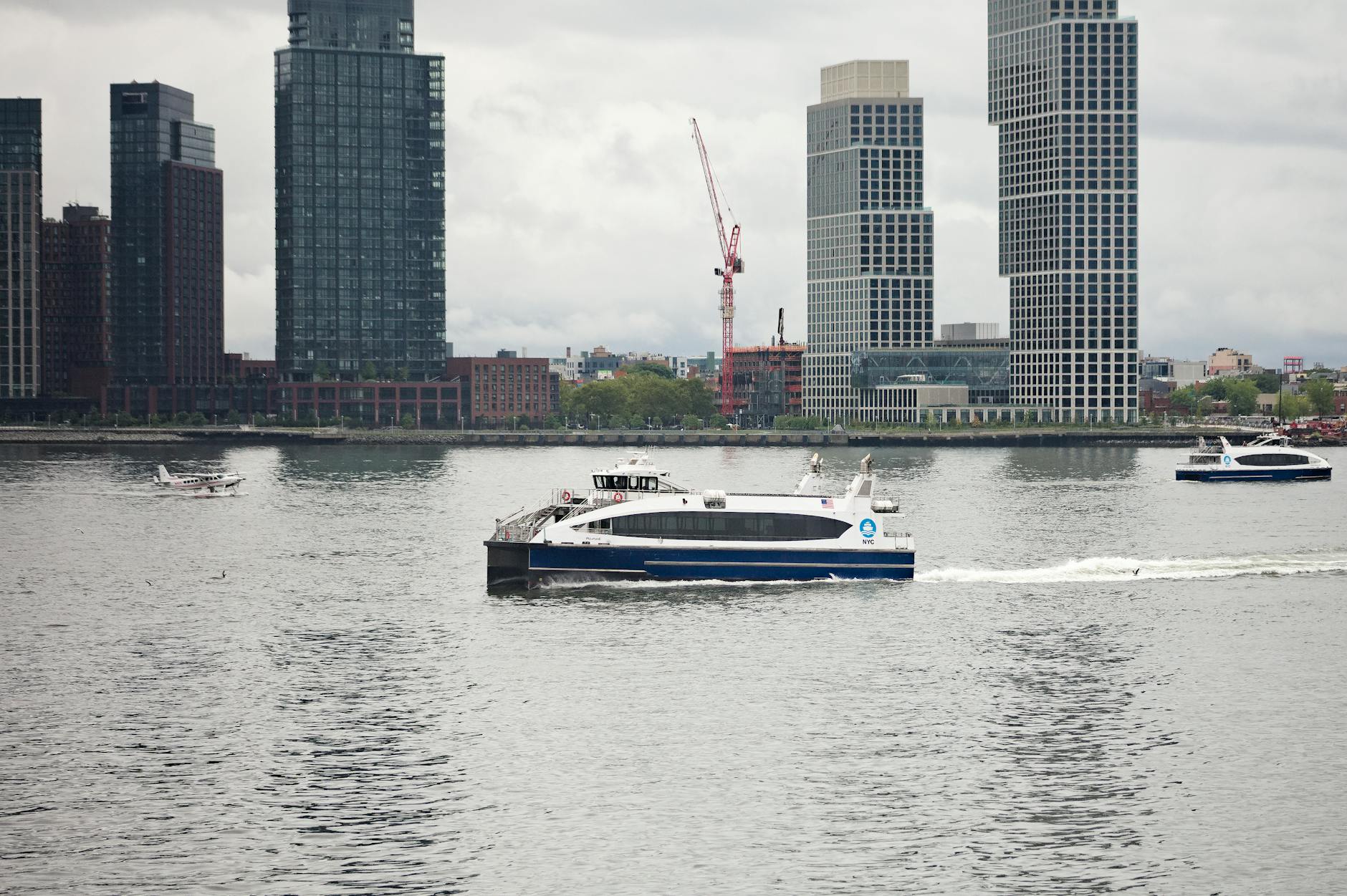 Deszcz nad rzeką w mieście, łodzie przy nabrzeżu i wieżowce w tle