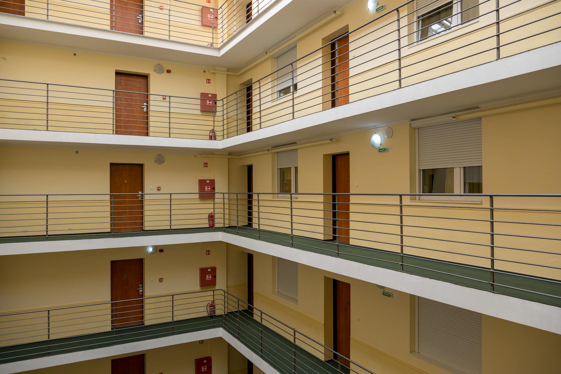 Klatka schodowa w bloku z metalową balustradą i drewnianymi drzwiami