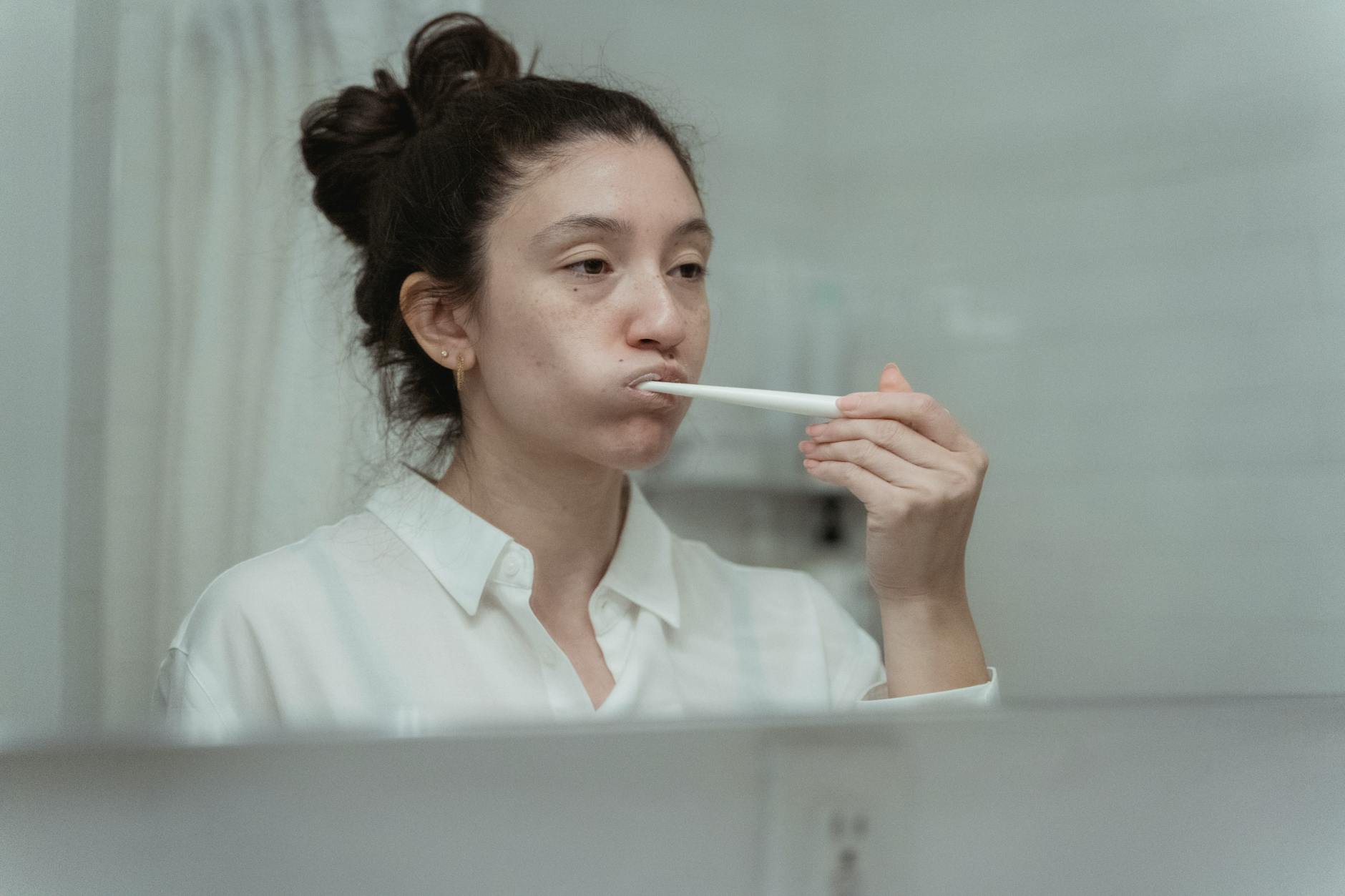 Kobieta myjąca zęby szczoteczką, dbająca o higienę jamy ustnej