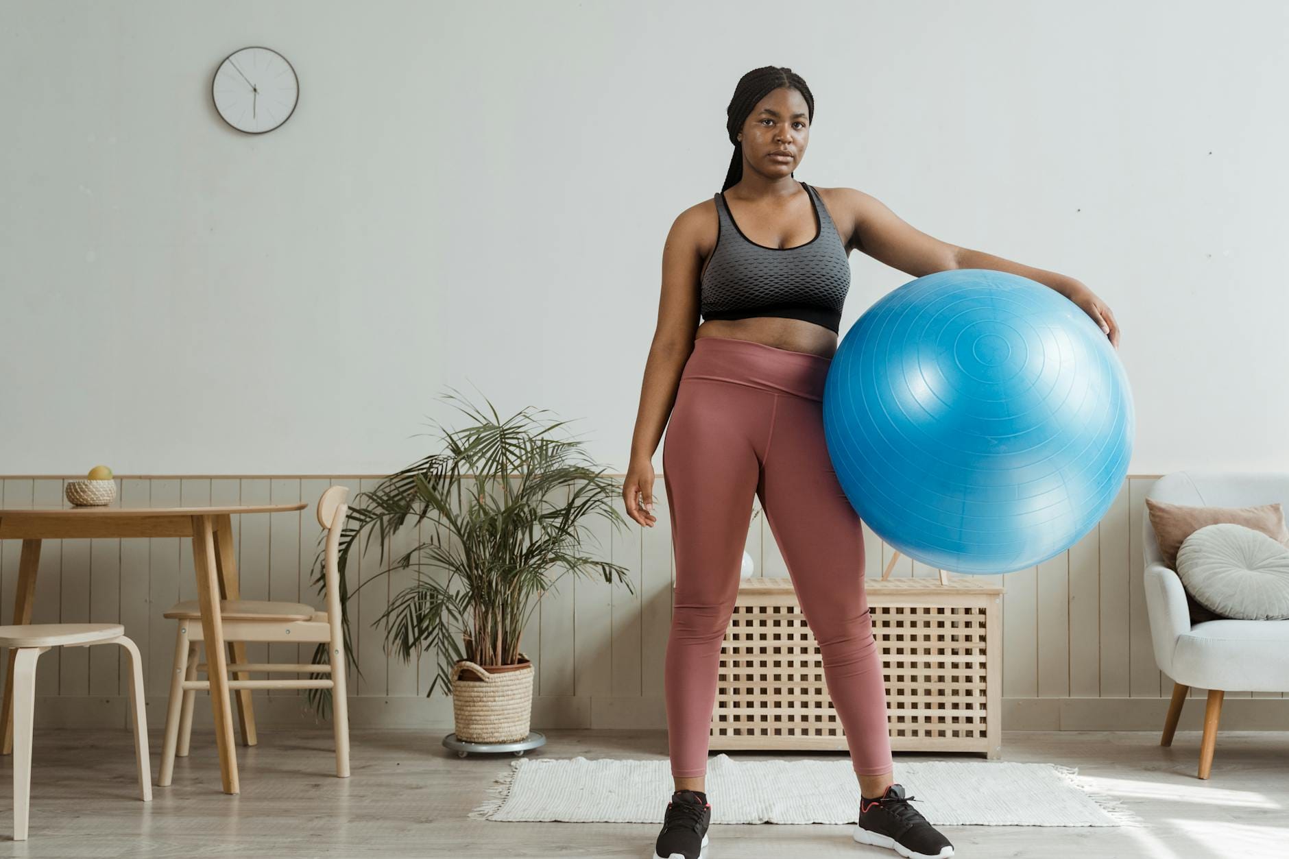 Kobieta trzyma niebieską piłkę do ćwiczeń w nowoczesnym salonie