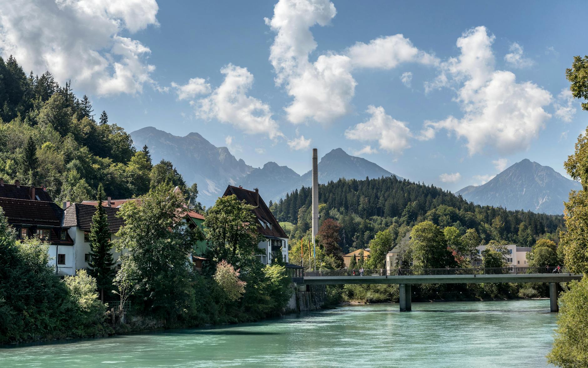 Most nad rzeką na tle alpejskich gór w słoneczny dzień