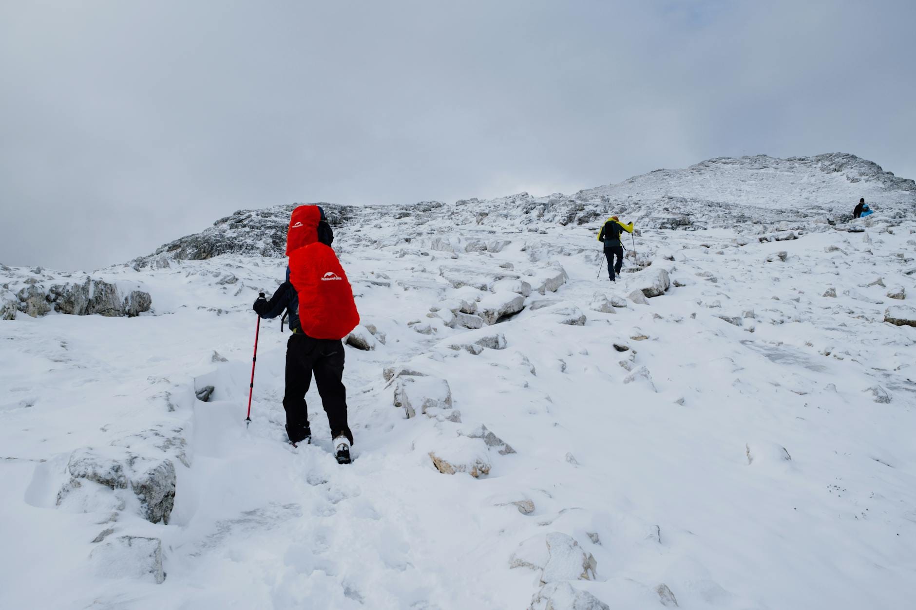 Turyści idący w górę zaśnieżonym szlakiem w górskiej dolinie
